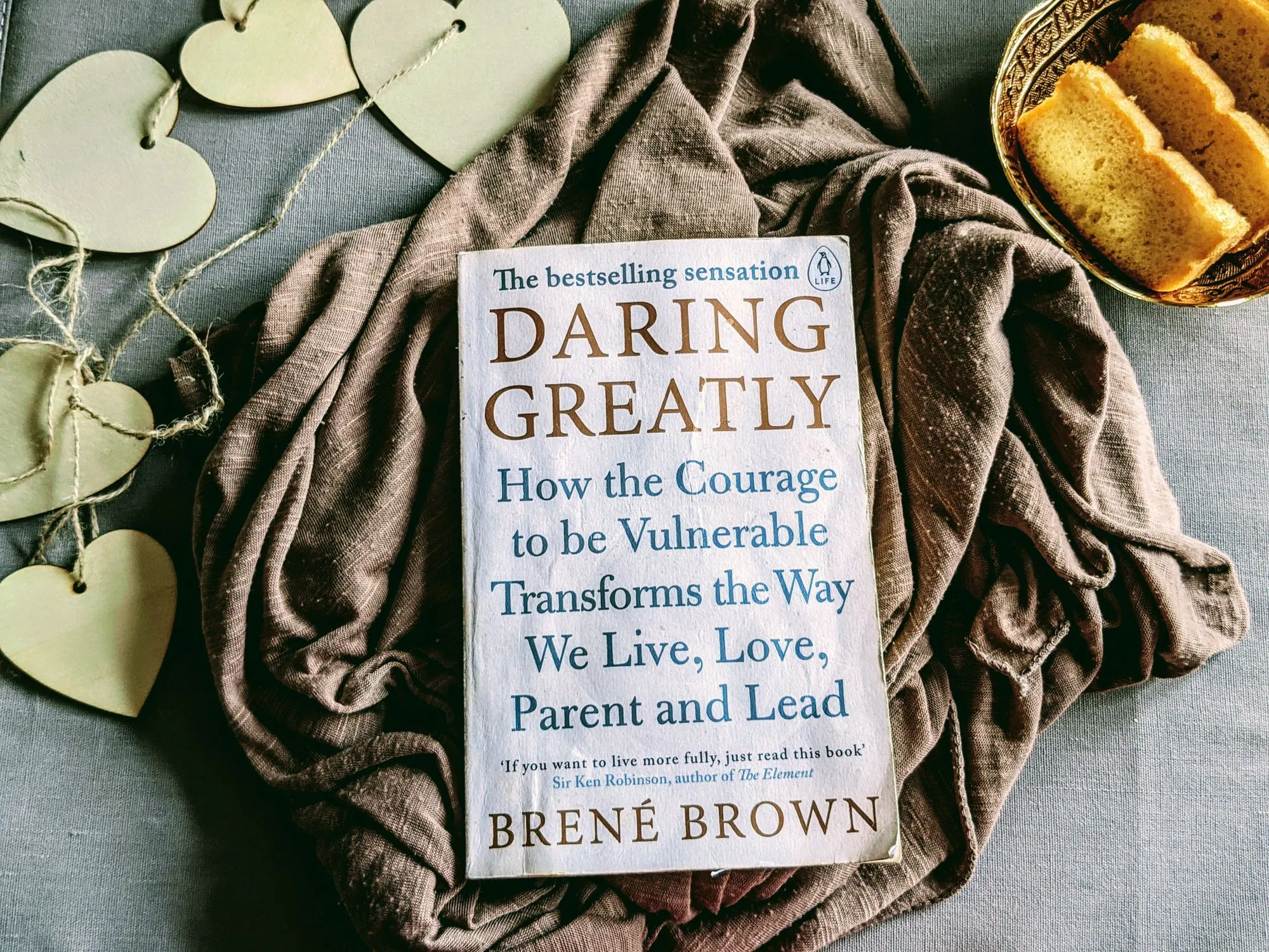 Daring Greatly by Brené Brown beside cake and heart-shaped decorations